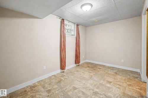 Recessed window with decorative metal grates, neutral wall finishes, drop ceiling, and patterned tile flooring - 10830 138 Street Nw, Edmonton, AB 