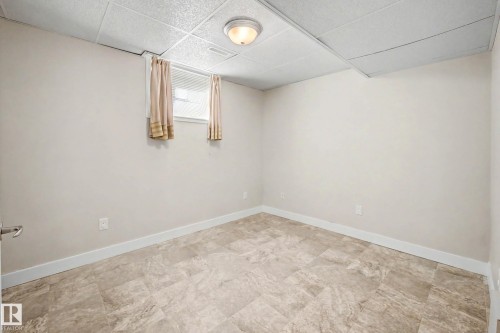 Drop ceiling with integrated flush-mount lighting, neutral wall paint, and tiled flooring - 10830 138 Street Nw, Edmonton, AB 