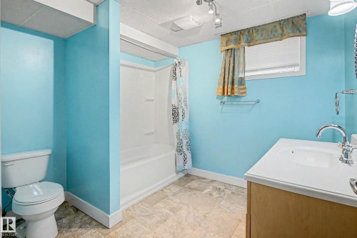 Bathroom with a full bathtub/shower combination, a vanity with an integrated sink, a toilet, and tile flooring - 10830 138 Street Nw, Edmonton, AB 