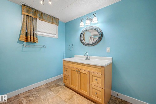 Wood-finish flooring with a light wood vanity, white countertop, and contemporary sink fixture - 10830 138 Street Nw, Edmonton, AB 