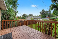 Expansive wood deck with a full railing overlooking a green lawn - 