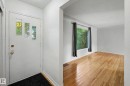 White entry door with decorative glass inserts, hardwood flooring, and a large window with privacy coverings - 10830 138 Street Nw, Edmonton, AB 