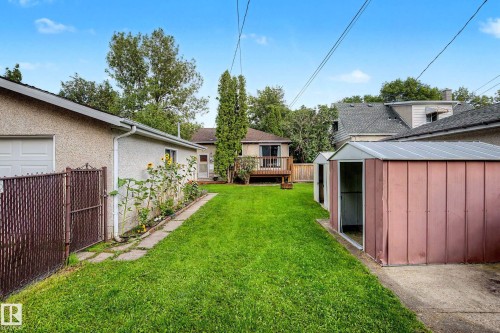 Expansive green lawn with a backyard deck, an attached garage, and two metal storage sheds - 10830 138 Street Nw, Edmonton, AB 