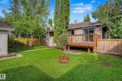 Expansive backyard featuring a wood deck, mature trees, privacy fencing, and a detached structure - 