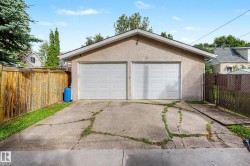 Two-car garage with stucco exterior and dual white panel doors, featuring a sloped concrete driveway - 