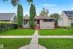 Stucco exterior with contrasting shutters, mature front yard trees, concrete walkway, and a landscaped front garden bed - 