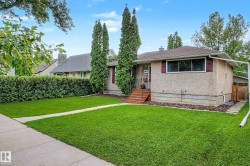 Stucco exterior with red window shutters, concrete walkway, front lawn, and mature hedges - 