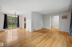 Polished wood-finish flooring throughout, bright white walls, recessed ceiling, sliding glass door to exterior, and a built-in chandelier - 
