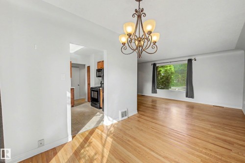 Hardwood flooring, decorative chandelier, light-toned walls, and an arched entryway - 10830 138 Street Nw, Edmonton, AB 