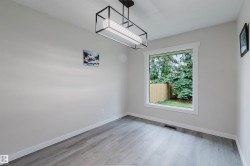 Light gray wood-finish flooring, a contemporary rectangular light fixture, and a large window with white trim - 