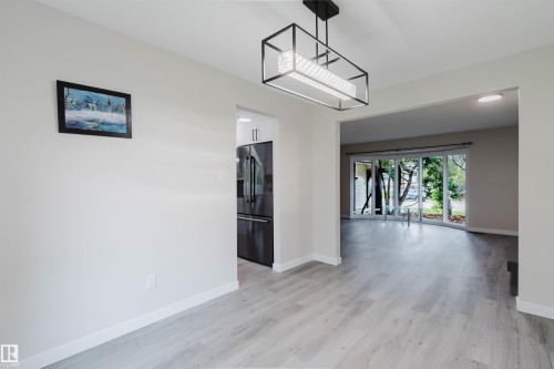 Wood-finish flooring throughout, framed opening, modern chandelier, recessed lighting, and large sliding glass door - 10423 35 Avenue Nw, Edmonton, AB 