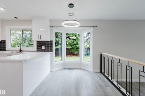 Contemporary kitchen with white cabinetry, a large kitchen island, and a black tile backsplash - 10423 35 Avenue Nw, Edmonton, AB 
