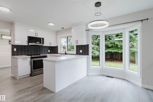 Modern kitchen featuring white cabinetry, a dark tiled backsplash, stainless steel appliances, and a prominent bay window - 10423 35 Avenue Nw, Edmonton, AB 