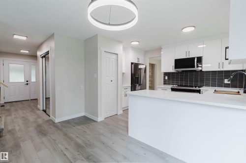 Modern kitchen featuring white cabinetry, a large kitchen island, and stainless steel appliances - 10423 35 Avenue Nw, Edmonton, AB 
