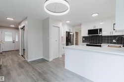 Modern kitchen featuring white cabinetry, a large kitchen island, and stainless steel appliances - 