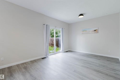 Wood-finish flooring, light-toned walls, and a sliding glass door providing access to an outdoor area - 10423 35 Avenue Nw, Edmonton, AB 