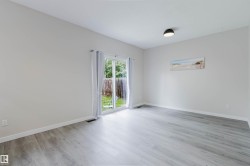 Wood-finish flooring, light-toned walls, and a sliding glass door providing access to an outdoor area - 
