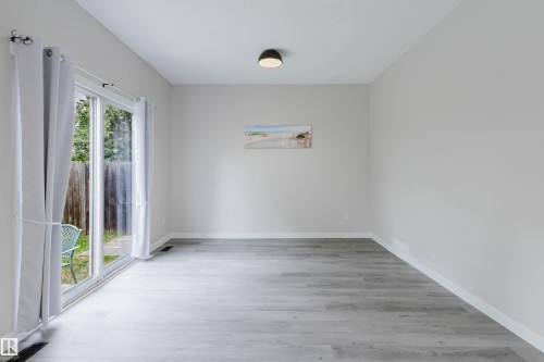Sliding glass door leading to the exterior, with wood-finish flooring and a flush-mount ceiling light - 10423 35 Avenue Nw, Edmonton, AB 