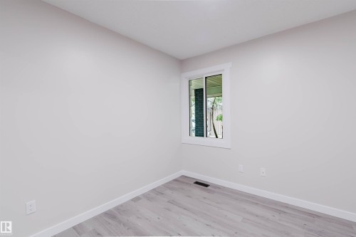Light-toned walls, wood-finish flooring, white window trim, and white baseboards - 10423 35 Avenue Nw, Edmonton, AB 