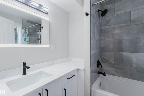 White vanity with matte black hardware, integrated sink, and white countertop - 10423 35 Avenue Nw, Edmonton, AB 