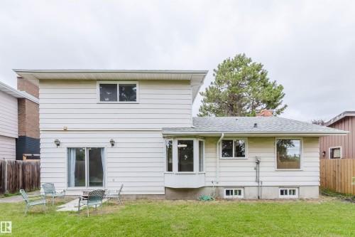 Expansive backyard featuring a manicured lawn, siding exterior, and sliding glass door access - 10423 35 Avenue Nw, Edmonton, AB 