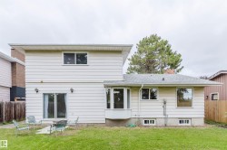 Expansive backyard featuring a manicured lawn, siding exterior, and sliding glass door access - 