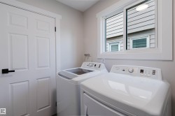 Laundry area featuring a window, white appliances, and a solid panel door with dark hardware - 
