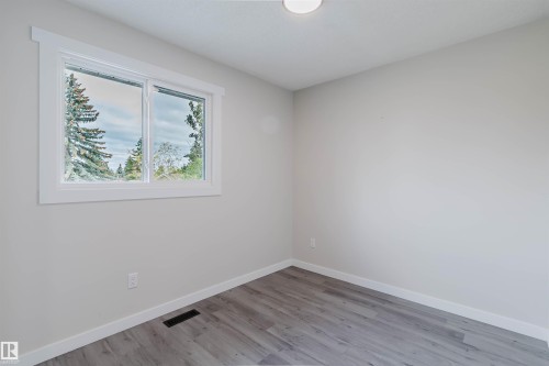 Recessed ceiling light, neutral wall paint, white trim, wood-finish flooring, and a double-pane window - 10423 35 Avenue Nw, Edmonton, AB 