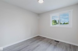 Light-toned walls, wood-finish flooring, white trim, and a ceiling-mounted light fixture - 