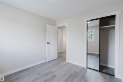 Light-toned wood-finish flooring, white paneled interior door, and mirrored closet doors - 