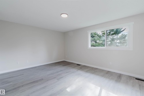 Light-toned wood-finish flooring complements the neutral wall color - 10423 35 Avenue Nw, Edmonton, AB 