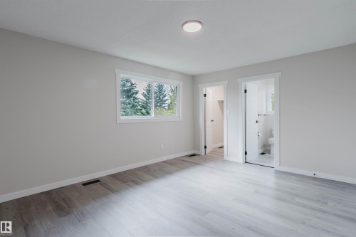 Light gray wood-finish flooring, white trim, recessed lighting, double window, and two doorways - 10423 35 Avenue Nw, Edmonton, AB 