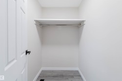 Closet with a single-panel door, black hardware, wood-finish flooring, white walls, and an integrated shelf with a hanging rod - 