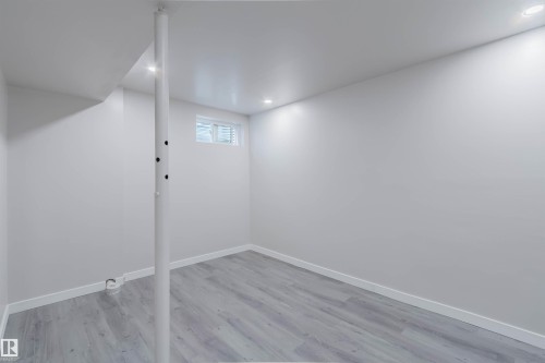 Recessed lighting, light gray wood-finish flooring, white walls, and a window with blinds - 10423 35 Avenue Nw, Edmonton, AB 