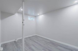 Recessed lighting, light gray wood-finish flooring, white walls, and a window with blinds - 