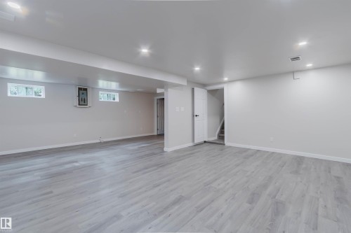 Expansive room featuring wood-finish flooring, recessed lighting, and bright white walls - 10423 35 Avenue Nw, Edmonton, AB 