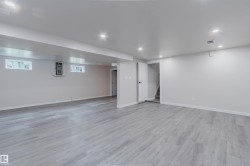 Expansive room featuring wood-finish flooring, recessed lighting, and bright white walls - 