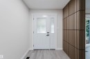 Entryway featuring a white door with frosted glass, an adjacent sidelight, contemporary wood-slat wall paneling, and light wood-finish flooring - 10423 35 Avenue Nw, Edmonton, AB 