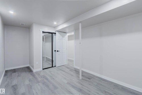 Recessed lighting, wood-finish flooring, white paneled door, mirrored closet doors, and white trim throughout - 10423 35 Avenue Nw, Edmonton, AB 
