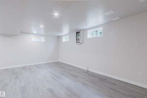 Expansive room featuring light wood-finish flooring, recessed lighting, and multiple windows - 10423 35 Avenue Nw, Edmonton, AB 