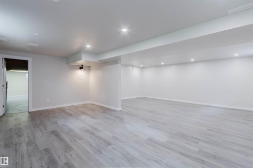 Spacious open concept room with wood-finish flooring, recessed lighting, and crisp white walls - 10423 35 Avenue Nw, Edmonton, AB 