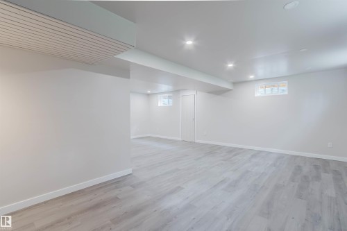 Spacious room with light wood-finish flooring, recessed lighting, and white walls - 10423 35 Avenue Nw, Edmonton, AB 