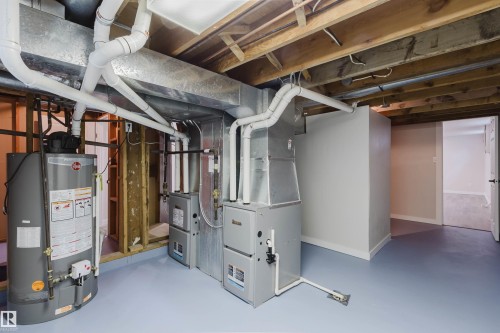 Exposed wood ceiling joists, two furnaces, water heater, painted concrete flooring, and a framed doorway - 10423 35 Avenue Nw, Edmonton, AB 