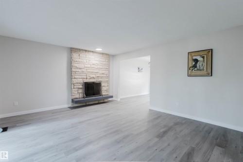 Stone-faced fireplace with a floating hearth, recessed lighting, and wood-finish flooring - 10423 35 Avenue Nw, Edmonton, AB 