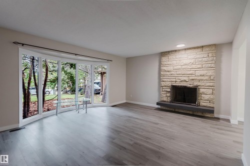 Hard-surface flooring, stone fireplace, and a wide bay window - 10423 35 Avenue Nw, Edmonton, AB 