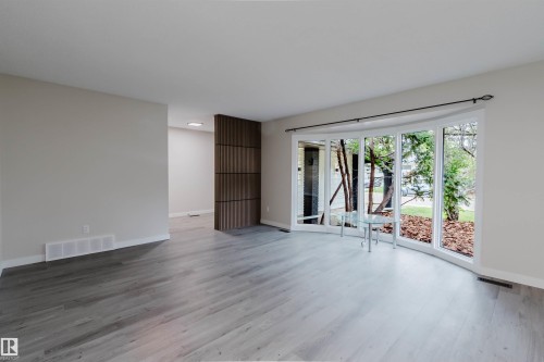 Curved bay window, light wood-finish flooring, white trim, recessed lighting, and a decorative partition wall - 10423 35 Avenue Nw, Edmonton, AB 