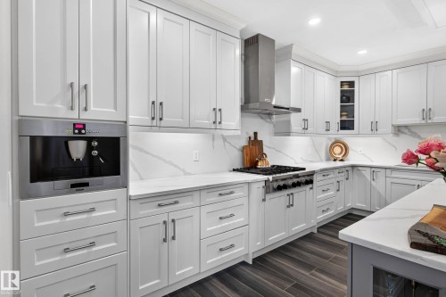 White shaker cabinetry, built-in coffee system, stainless steel gas range with hood, granite countertops. - 94 Westlin Drive, Leduc, AB 