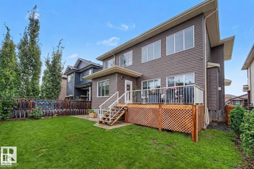 Expansive green lawn, multi-story siding exterior, private wood fencing, upper-level deck, and mature trees - 94 Westlin Drive, Leduc, AB 