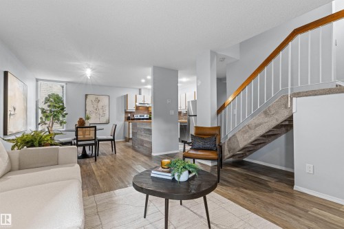 Open-concept living space with wood-finish flooring, a contemporary staircase, and a dining area - #7 10032 113 St Nw, Edmonton, AB 