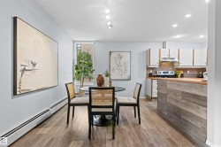 Open-concept living space featuring wood-finish flooring, recessed lighting, a kitchen with white cabinetry, a wood-finish countertop, and a tiled backsplash - 